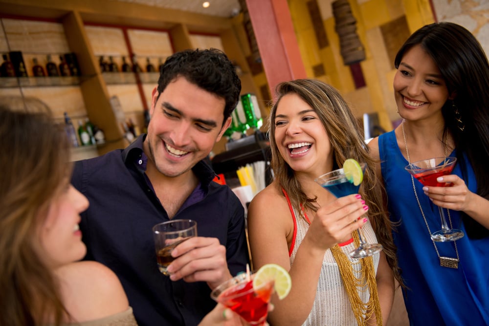 Happy group of friends at the bar having drinks